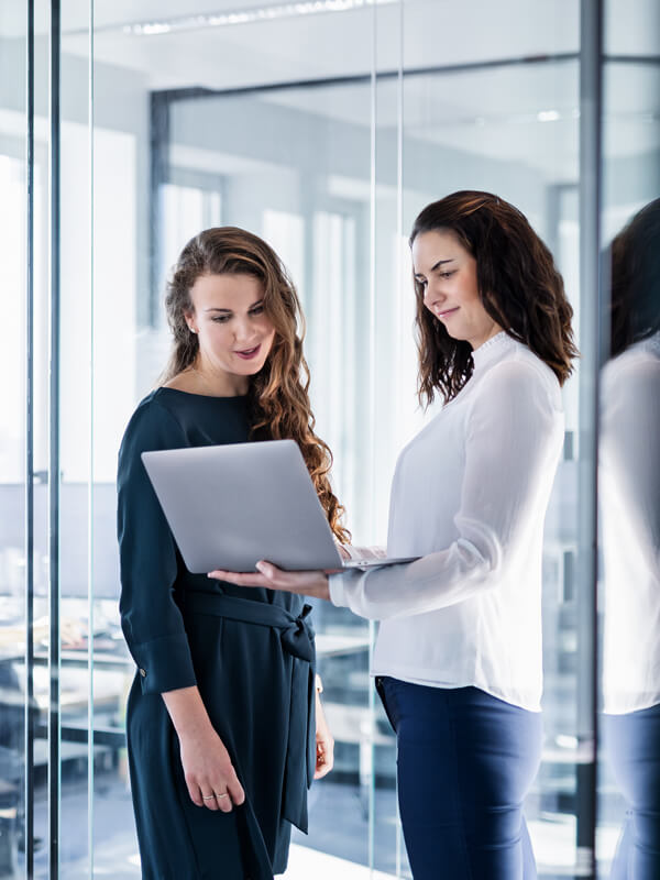 Two business women looking at a laptop and talking about the newest offers