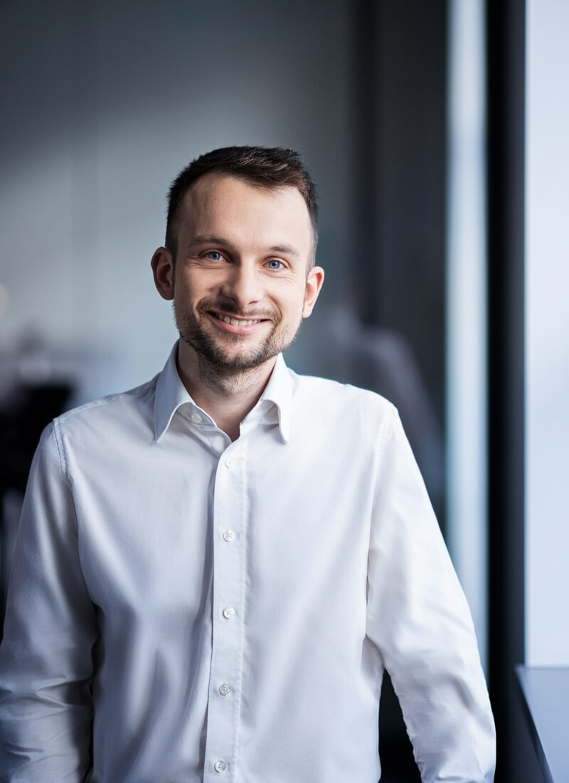 A young male team member in an office and smiling for the camera