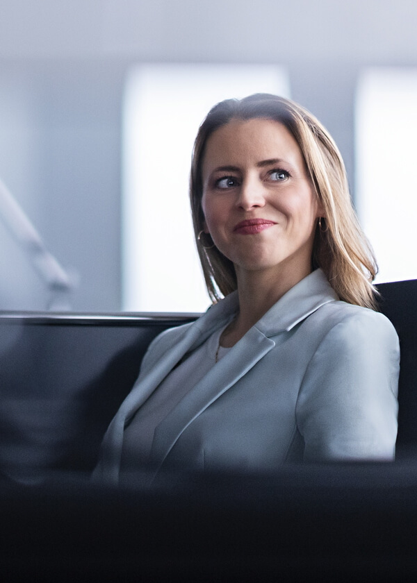 A young business woman who is sitting in an office and has a satisfied smile