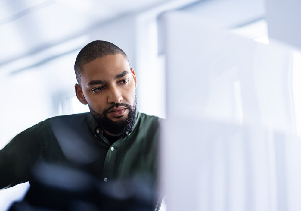 A young businessman sitting in an office and looking at offers on his computer