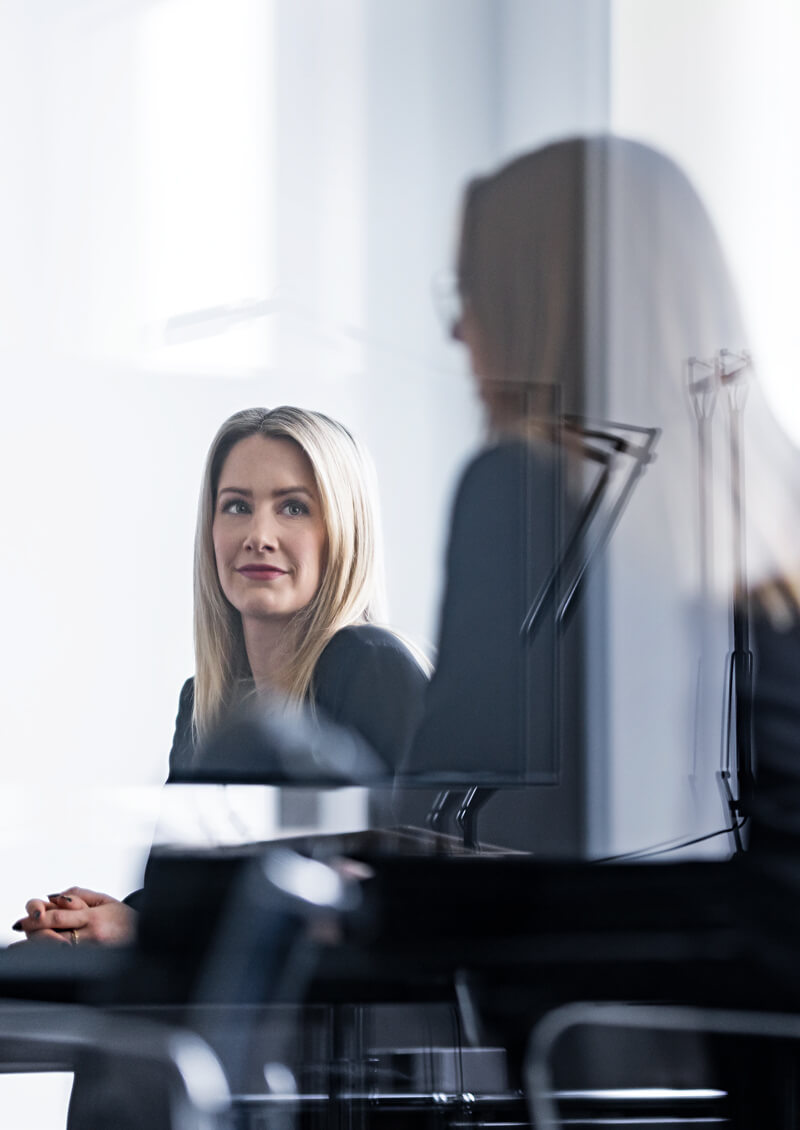 One female executive making a presentation while another female employee listens attentively. 